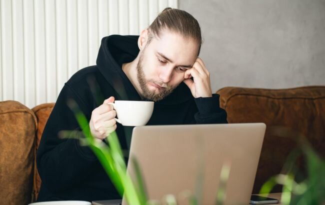 tired_young_man_working_on_a_laptop_with_a_cup_of_coffee_650x410.jpg